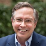 Jim Fruchterman standing in front of a hedge, smiling